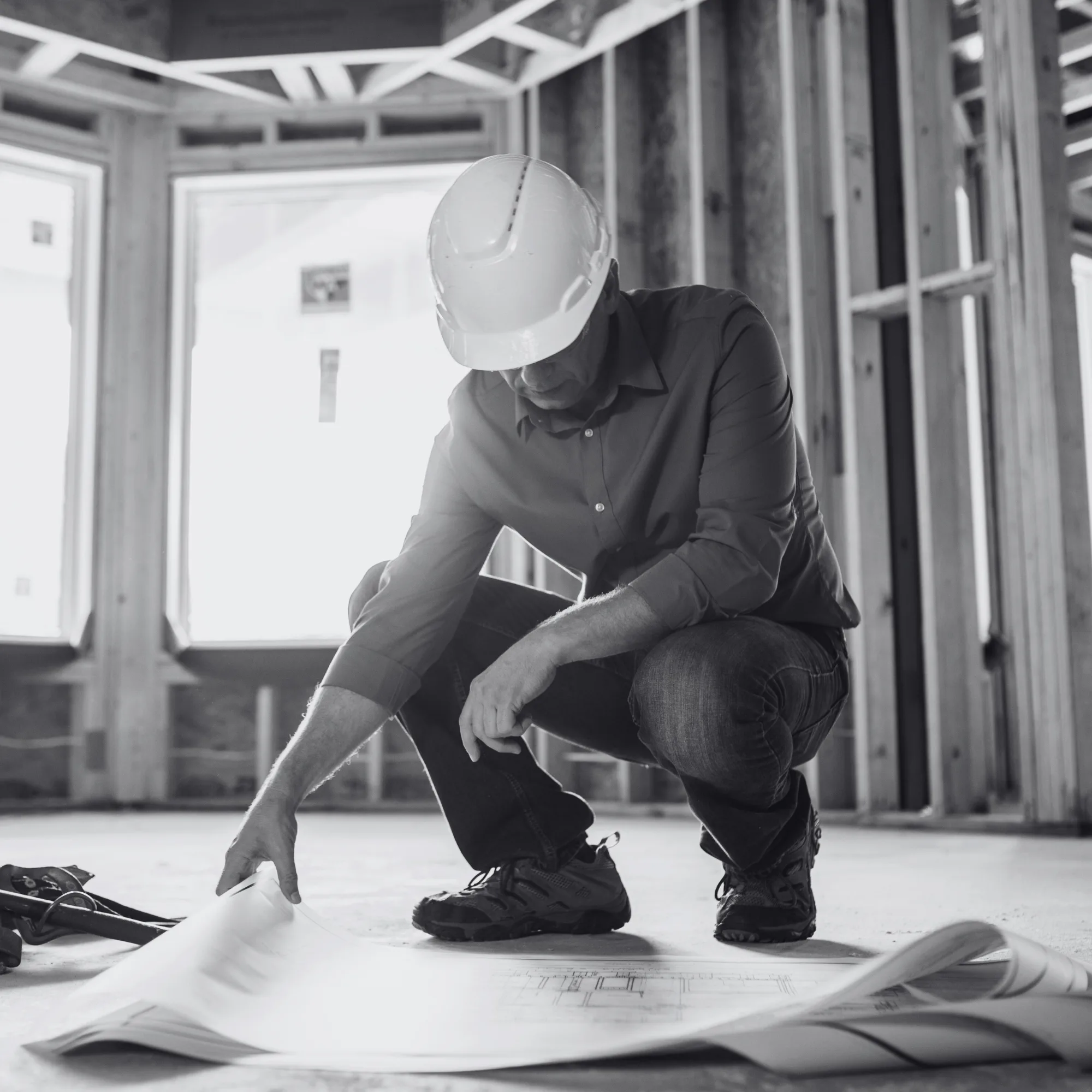 an image of a contractor looking at the plans for a room in an unfinished construction area